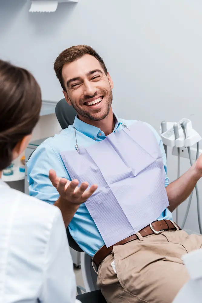 Man Laughing in Dentist Chair with Dental Assistant
